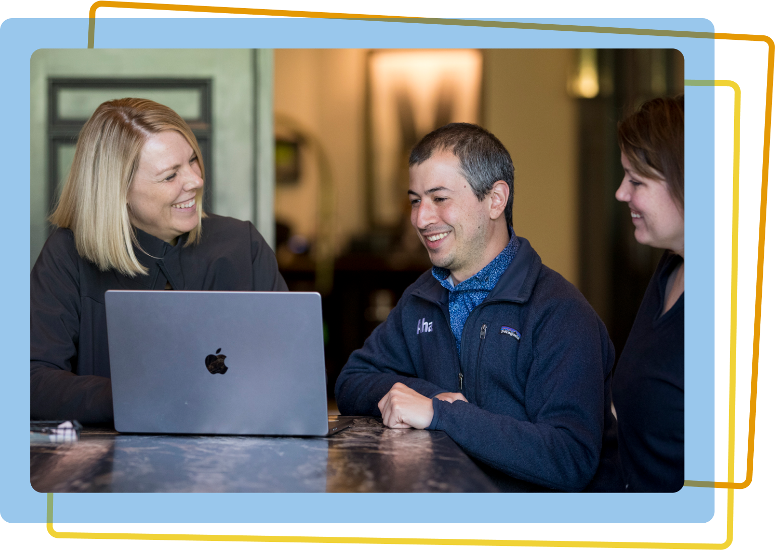 Two women and one man working together on a laptop